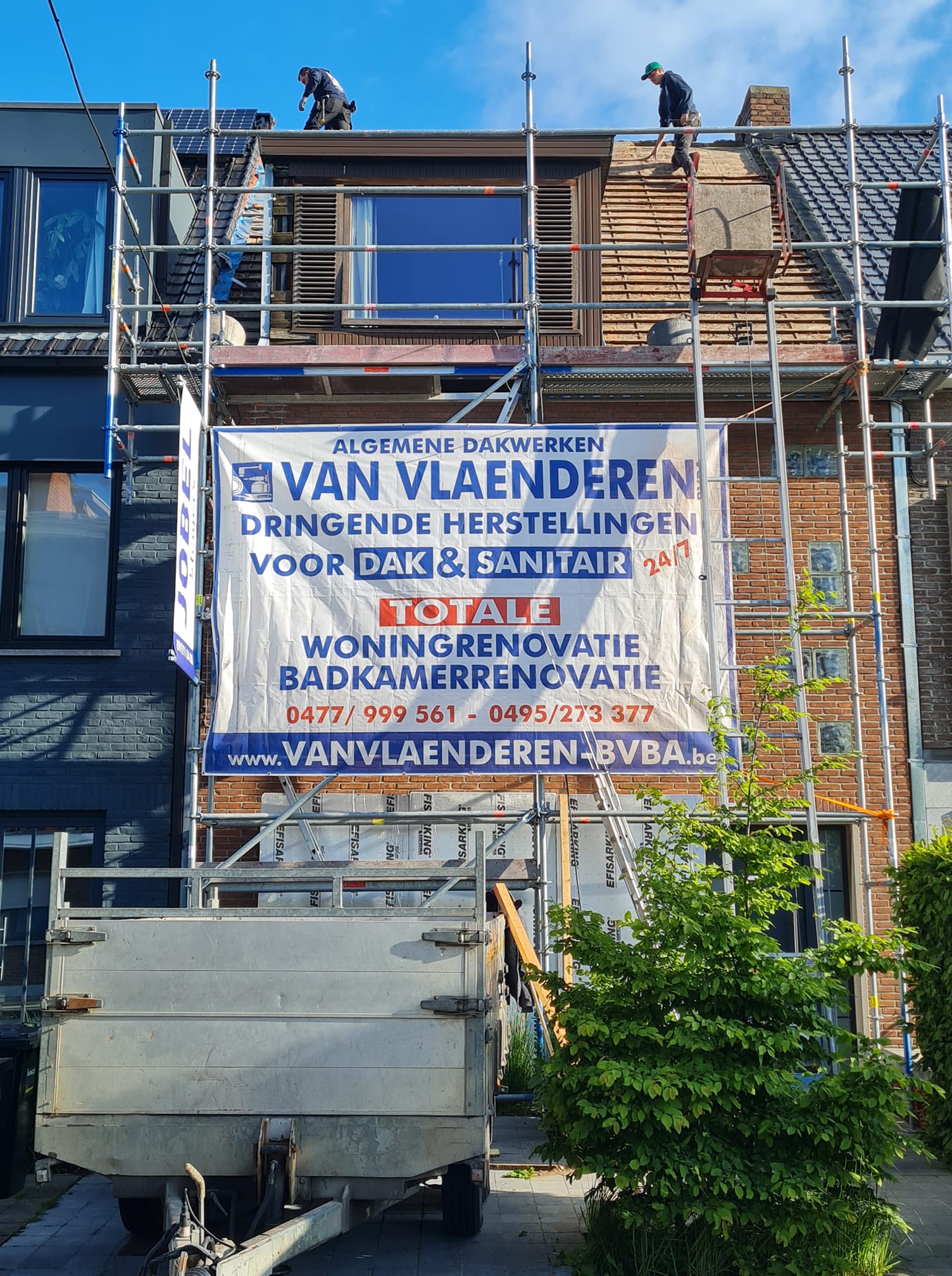 Rijwoning in renovatie met steigers en spandoek van Dakwerken Van Vlaenderen